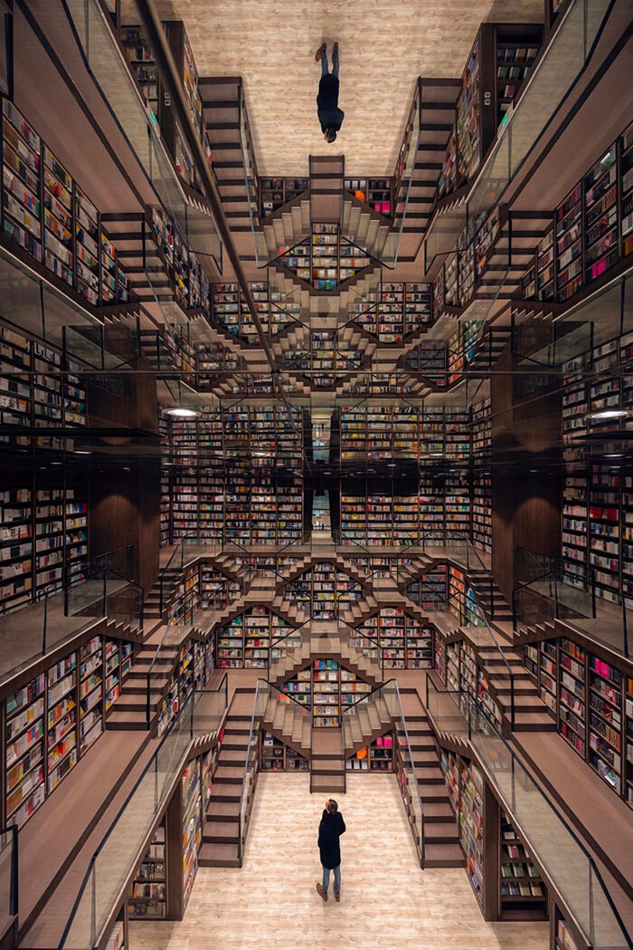 M.C. Escher Woodcut Inspired Bookstore With Mirrored Ceiling and Criss-Crossed Stairwells